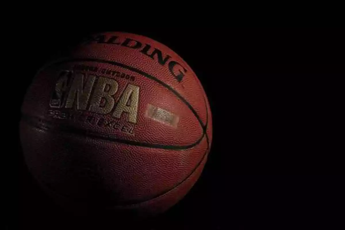 Balón de baloncesto Spalding con logotipo de la NBA sobre fondo negro.