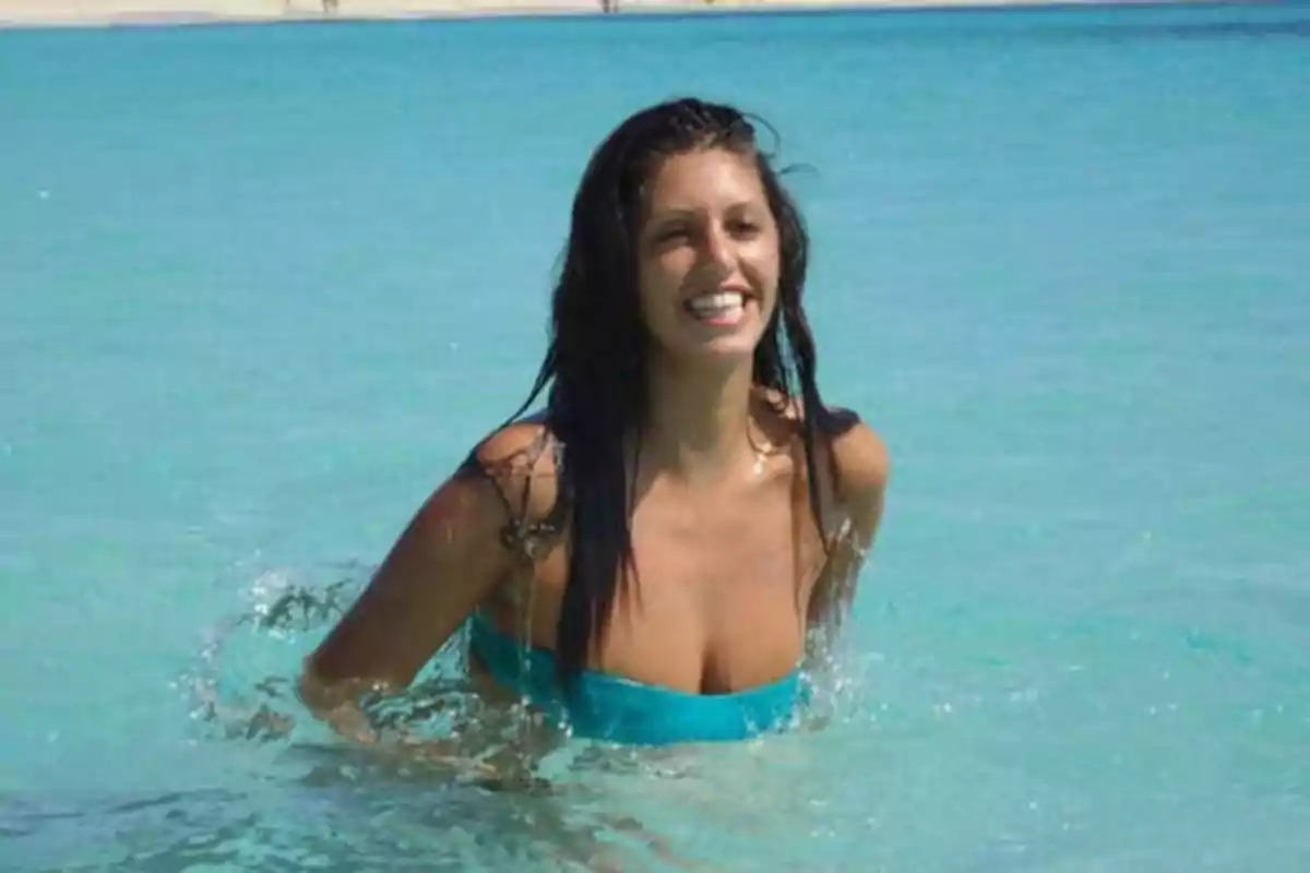 Mujer sonriendo mientras se baña en el mar con agua cristalina.