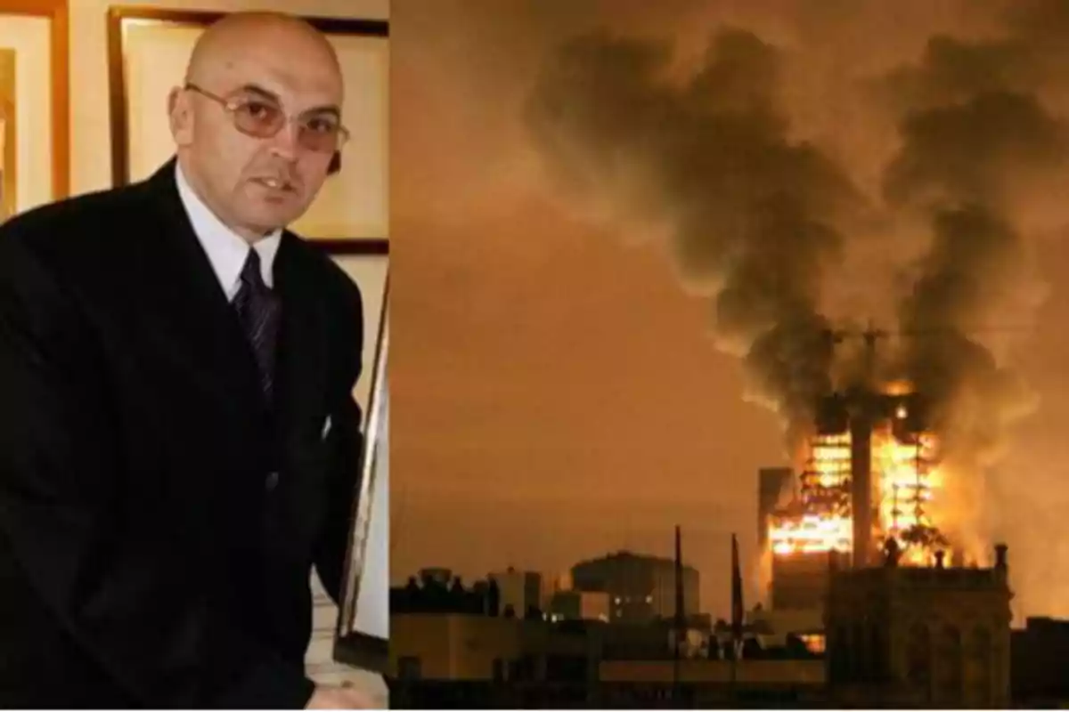 Un hombre con gafas y traje oscuro está a la izquierda de la imagen, mientras que a la derecha se observa un edificio en llamas con una gran columna de humo.