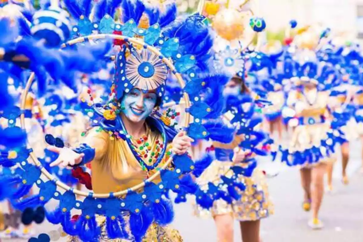 Personas disfrazadas con trajes coloridos y plumas azules participan en un desfile festivo.
