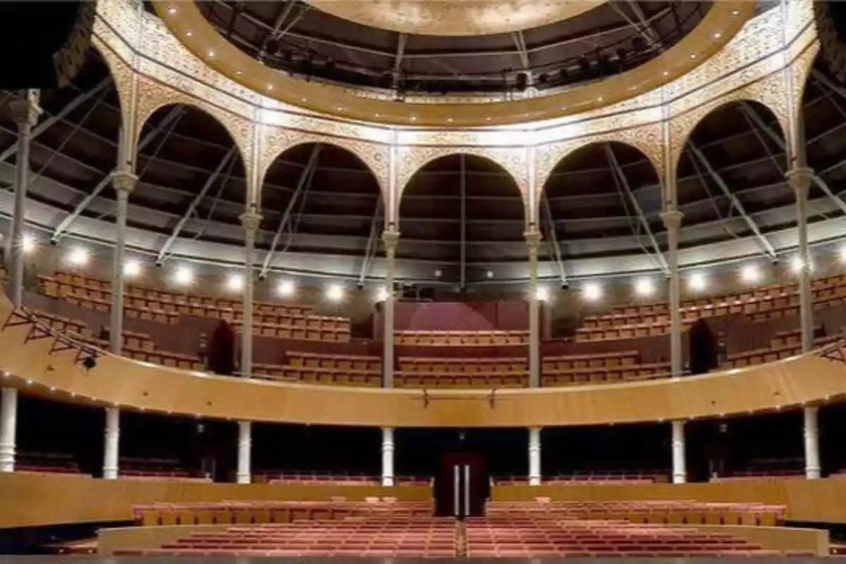Interior de un teatro con múltiples niveles de asientos y una estructura arquitectónica con arcos y columnas decorativas.