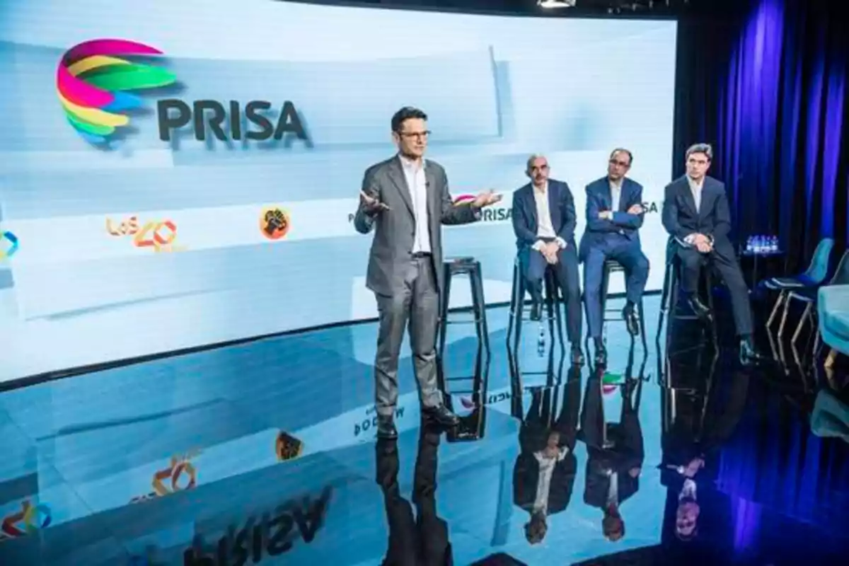 Un grupo de hombres en un escenario con el logotipo de PRISA y otros logotipos de medios de comunicación en el fondo.