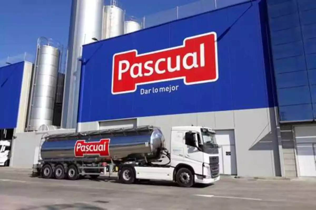 Camión cisterna de la empresa Pascual estacionado frente a una planta industrial con el logotipo de la compañía en un gran cartel azul.