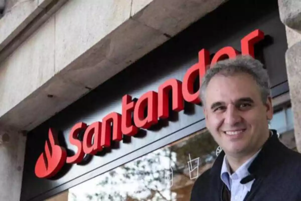 Hombre sonriendo frente a una sucursal del banco Santander.