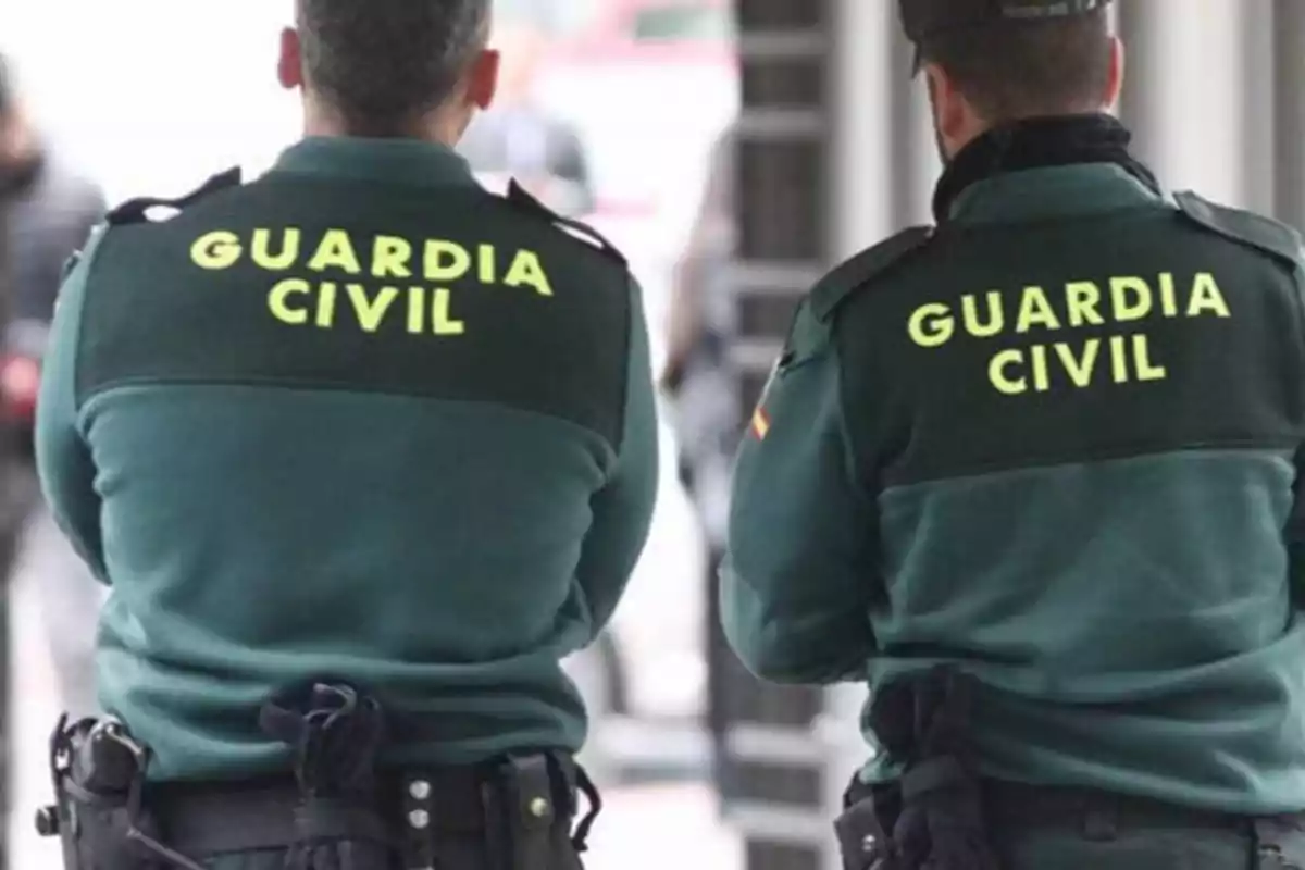 Dos agentes de la Guardia Civil de espaldas con uniformes verdes.