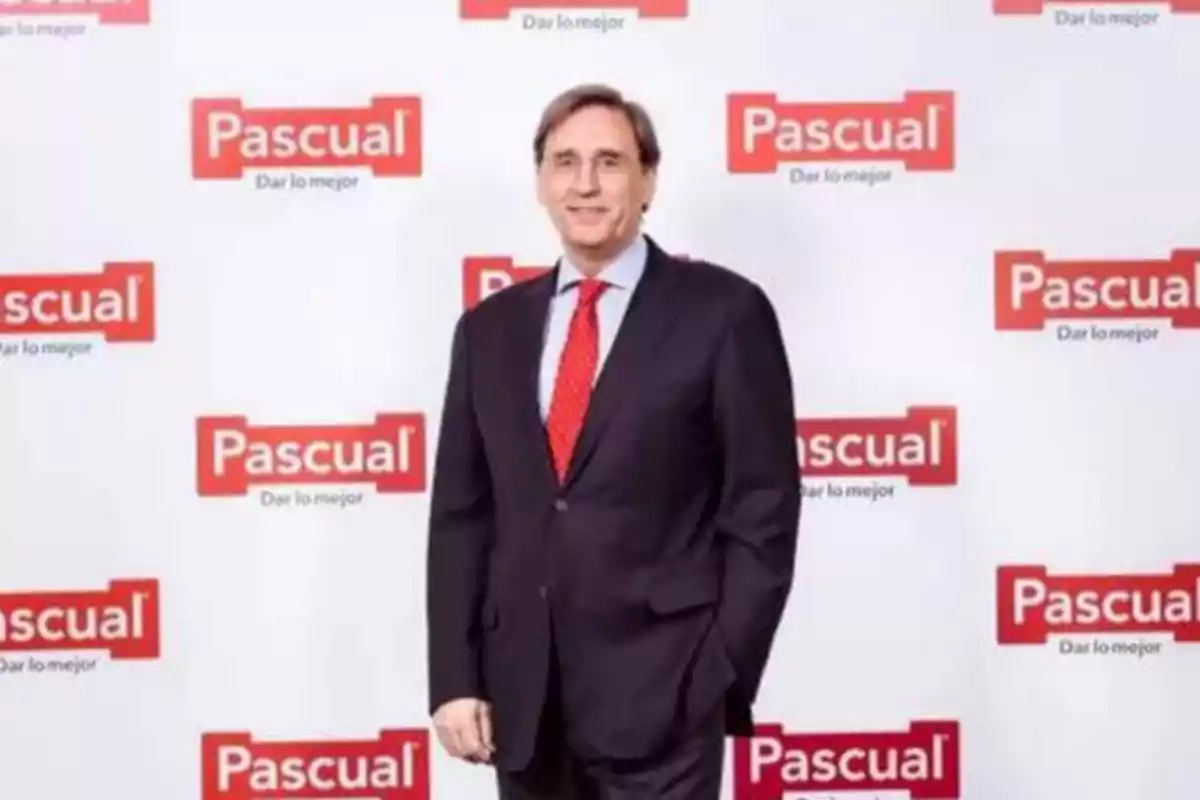 Hombre de traje y corbata roja posando frente a un fondo con el logo de Pascual.