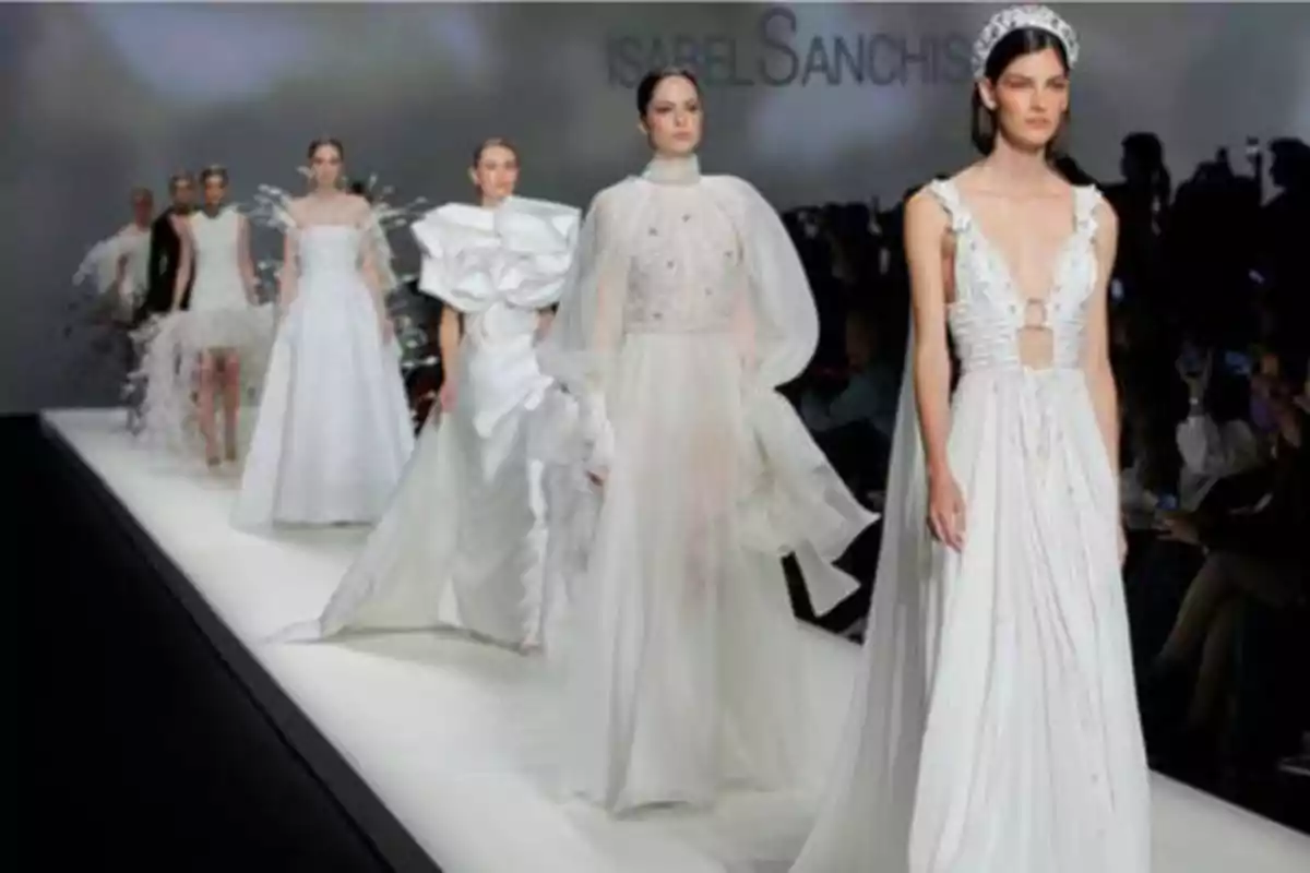 Desfile de moda con modelos luciendo vestidos blancos en una pasarela.