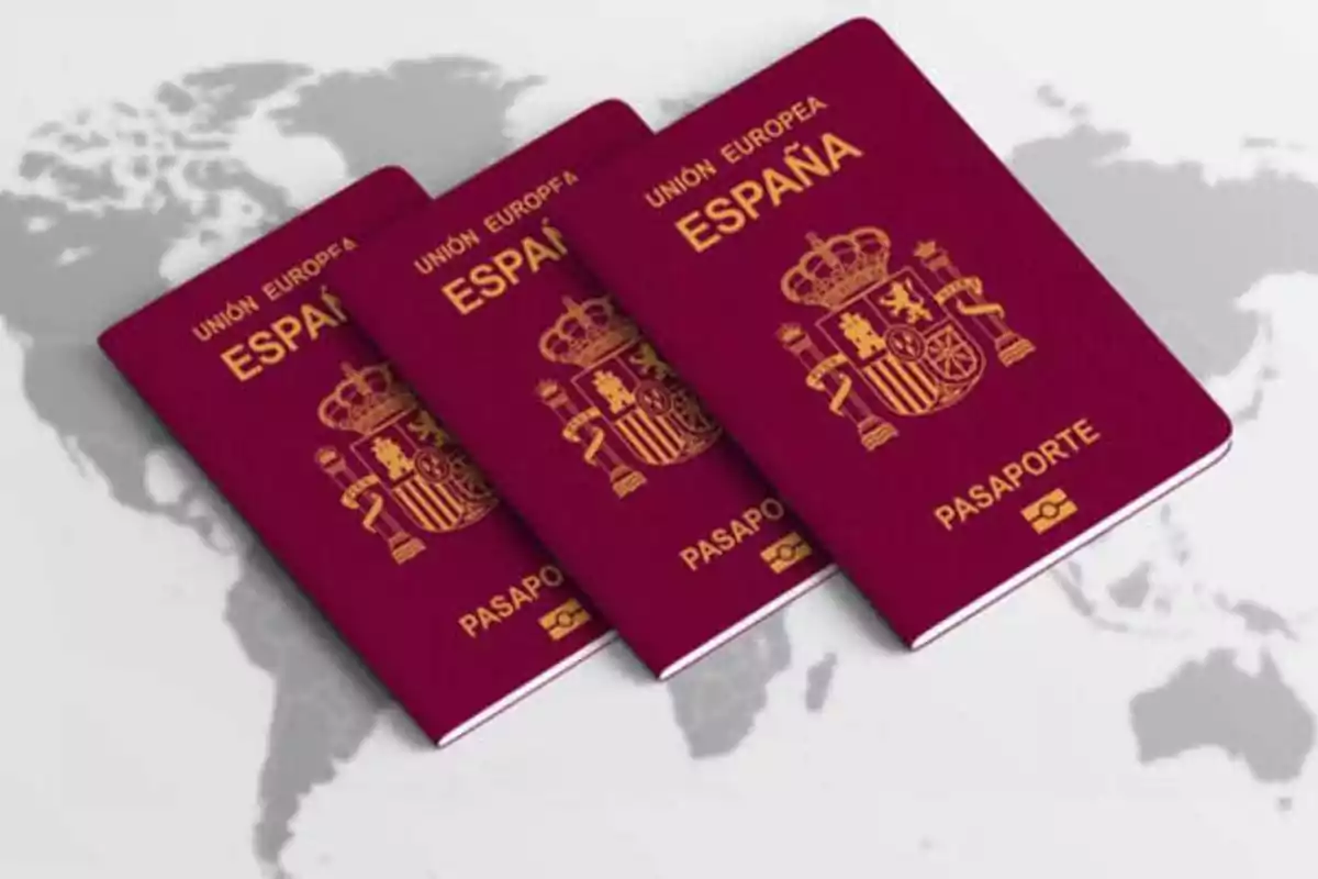 Tres pasaportes españoles sobre un fondo de mapa mundial.