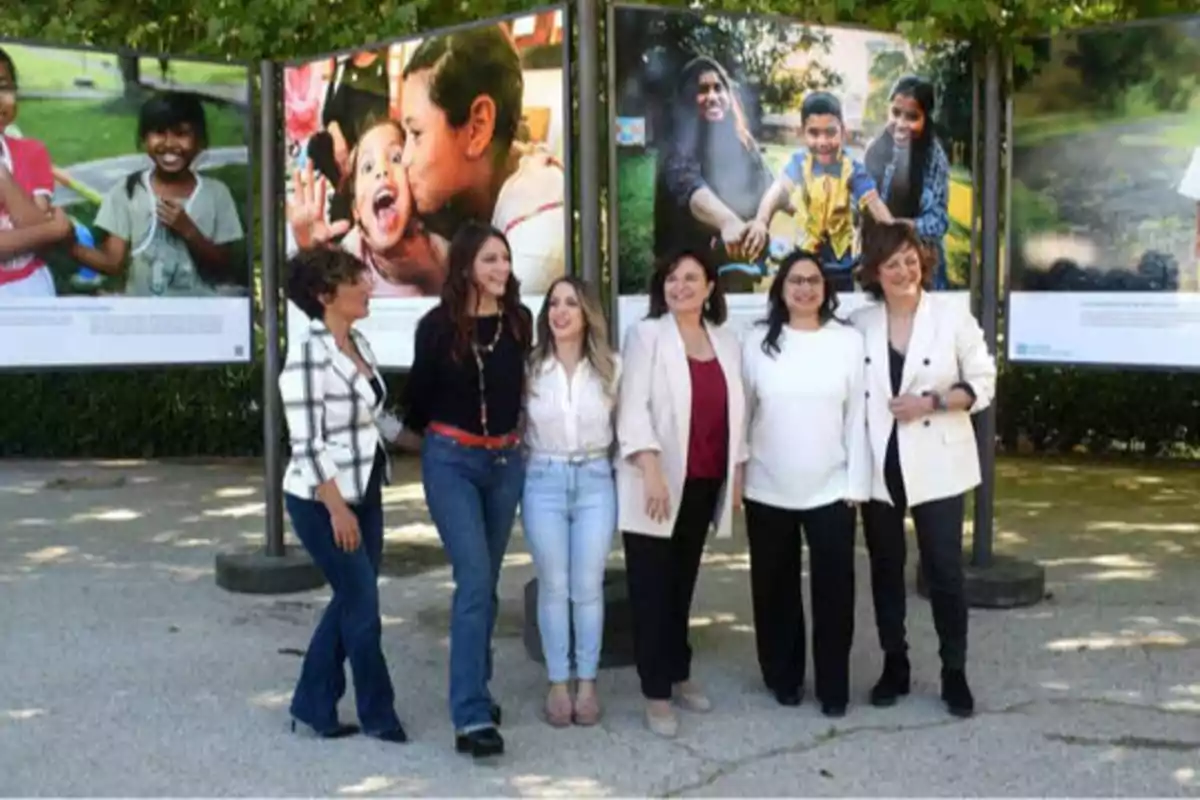 Un grupo de mujeres posando frente a una exposición de fotografías al aire libre.