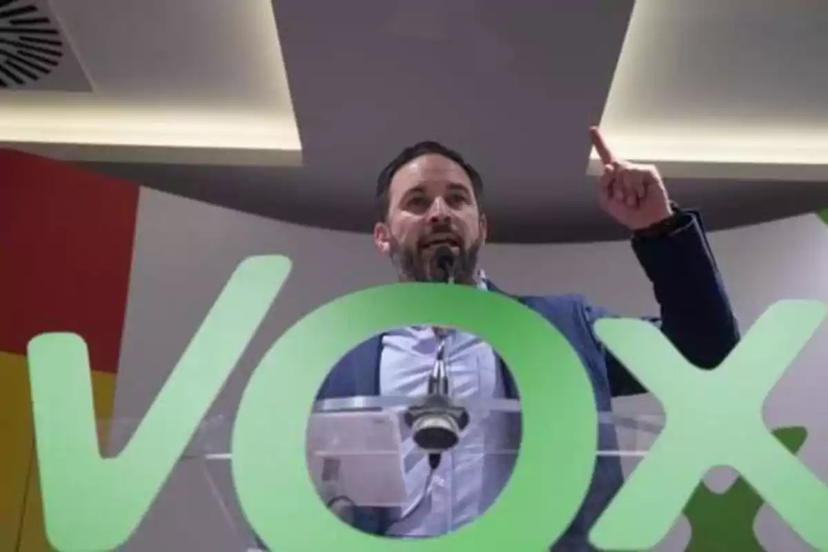 Hombre hablando en un podio con el logo de VOX en primer plano.