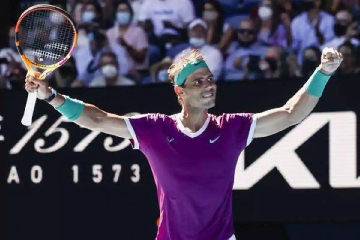 Tenista celebrando con los brazos en alto en una cancha de tenis.