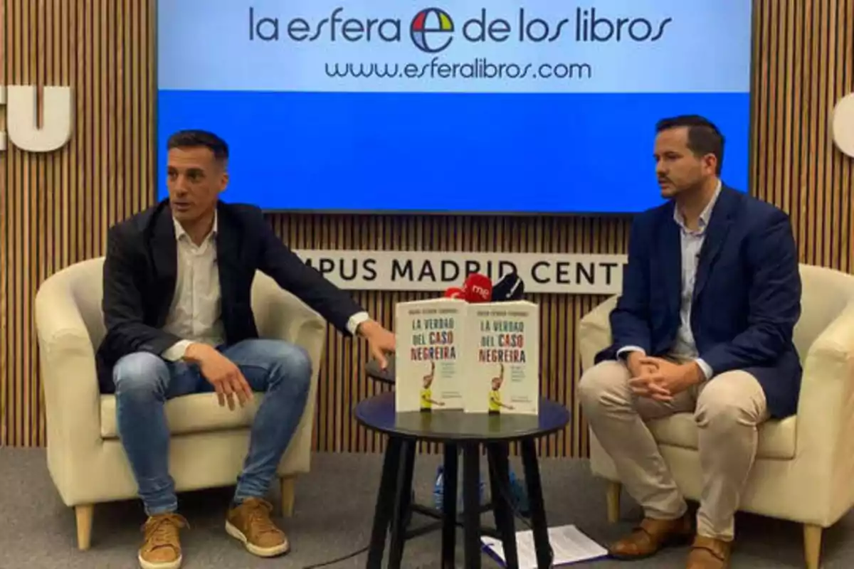 Dos hombres sentados en sillones durante una presentación de un libro titulado "La verdad del caso Negreira" en un evento de La Esfera de los Libros en el Campus Madrid Centro.