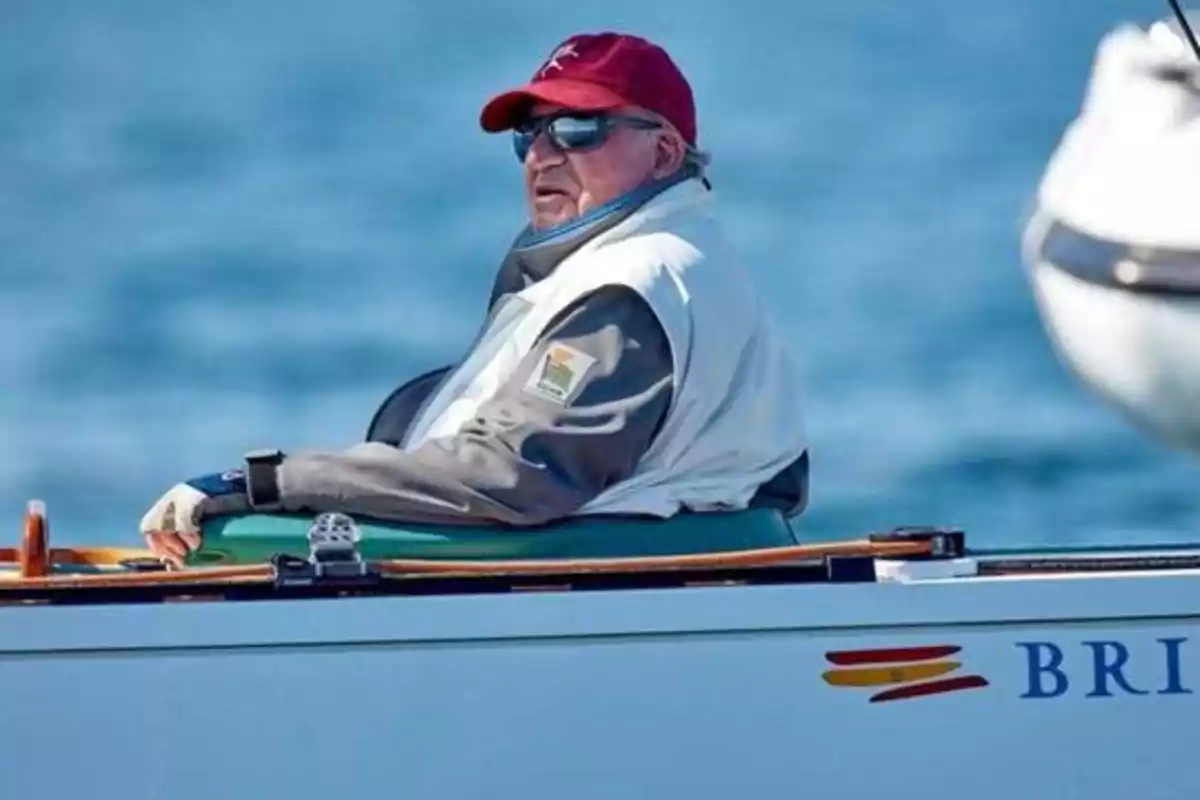 Un hombre con gorra roja y gafas de sol está sentado en un bote en el mar.