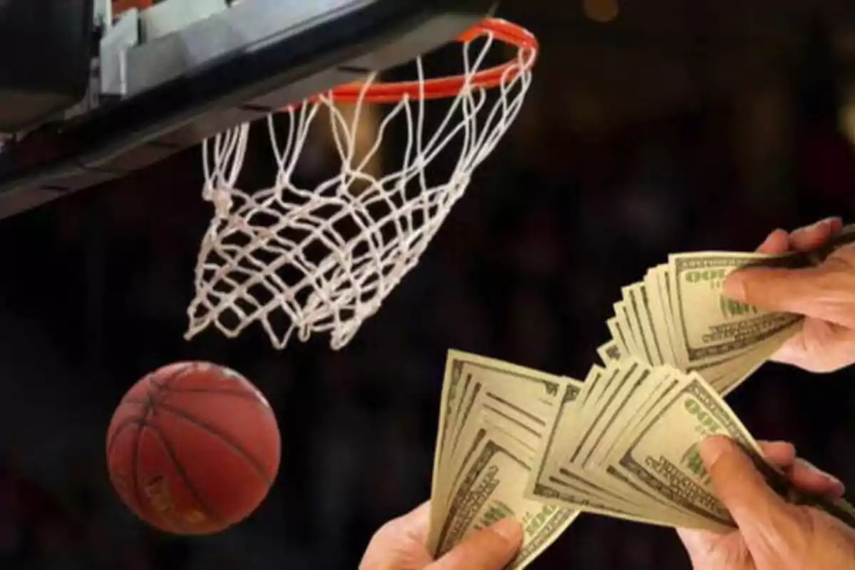 Una pelota de baloncesto cerca de una canasta con manos sosteniendo billetes de dólar en primer plano.