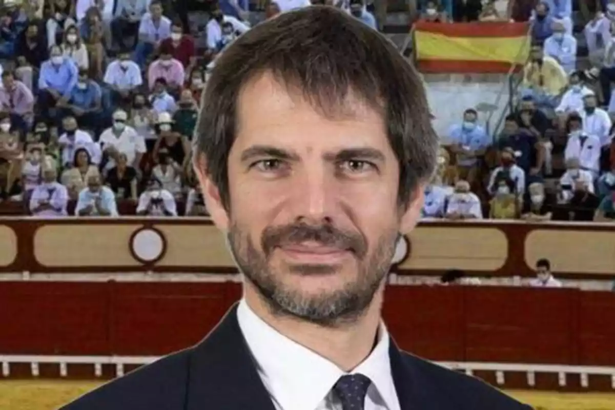 Un hombre con barba y traje frente a una multitud en una plaza de toros.