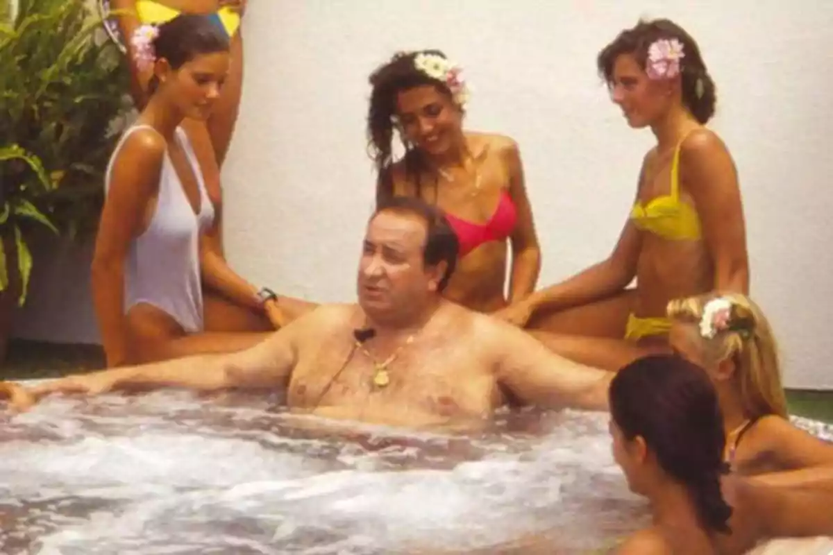 Un hombre en un jacuzzi rodeado de varias mujeres en traje de baño.