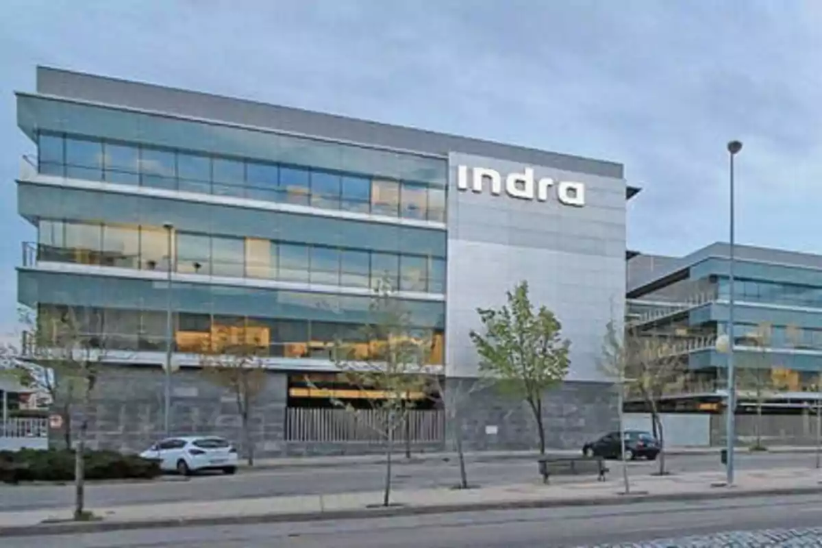 Edificio moderno de oficinas con el logo de Indra en la fachada.