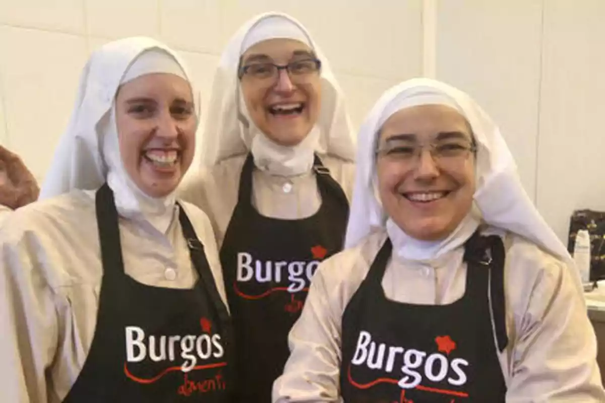 Tres monjas sonrientes con delantales negros que dicen "Burgos alimenta".