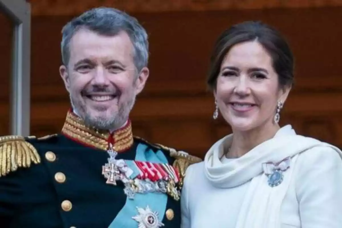 Una pareja sonriente vestida con trajes formales y elegantes.