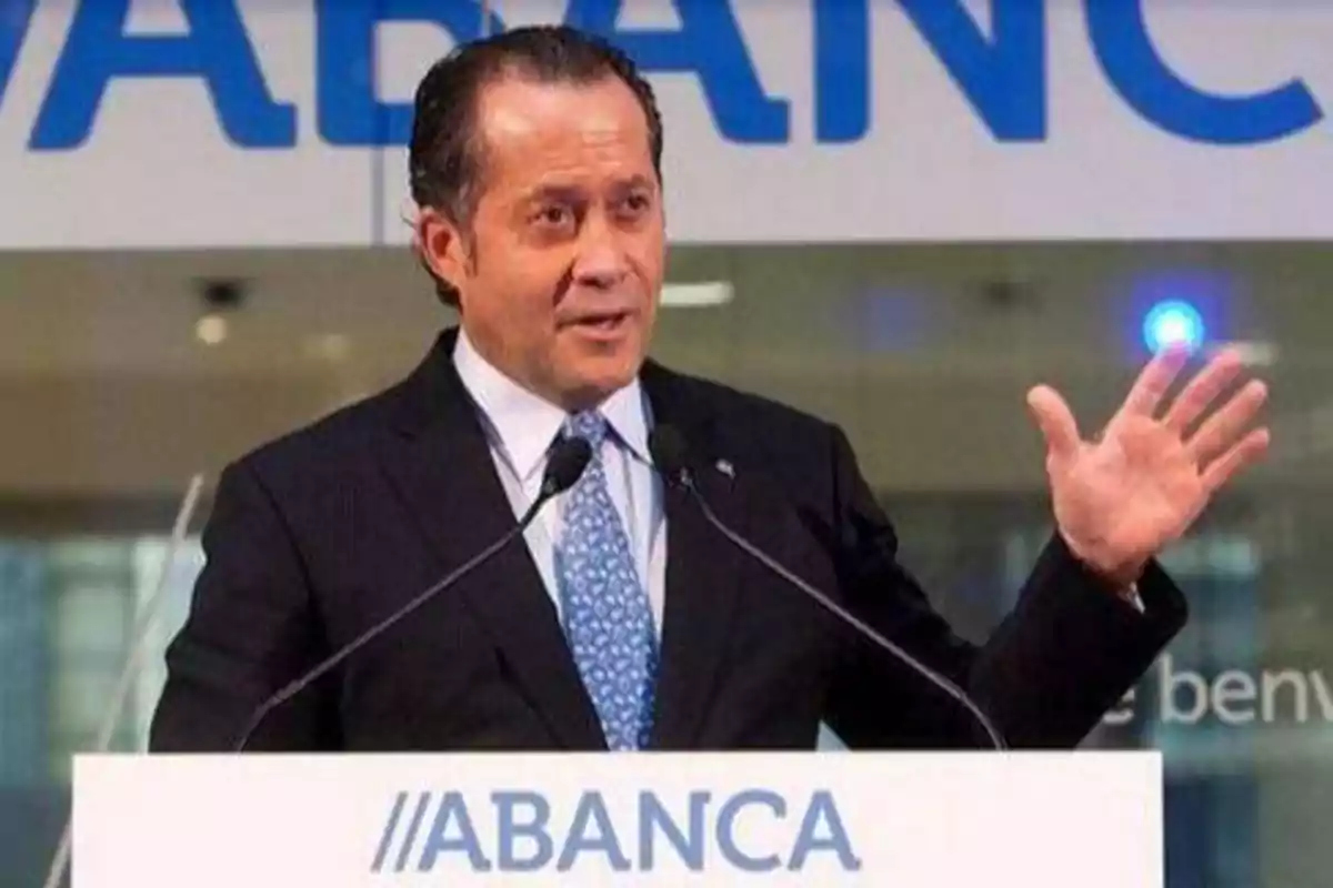 Un hombre en traje y corbata habla en un podio con el logotipo de ABANCA.