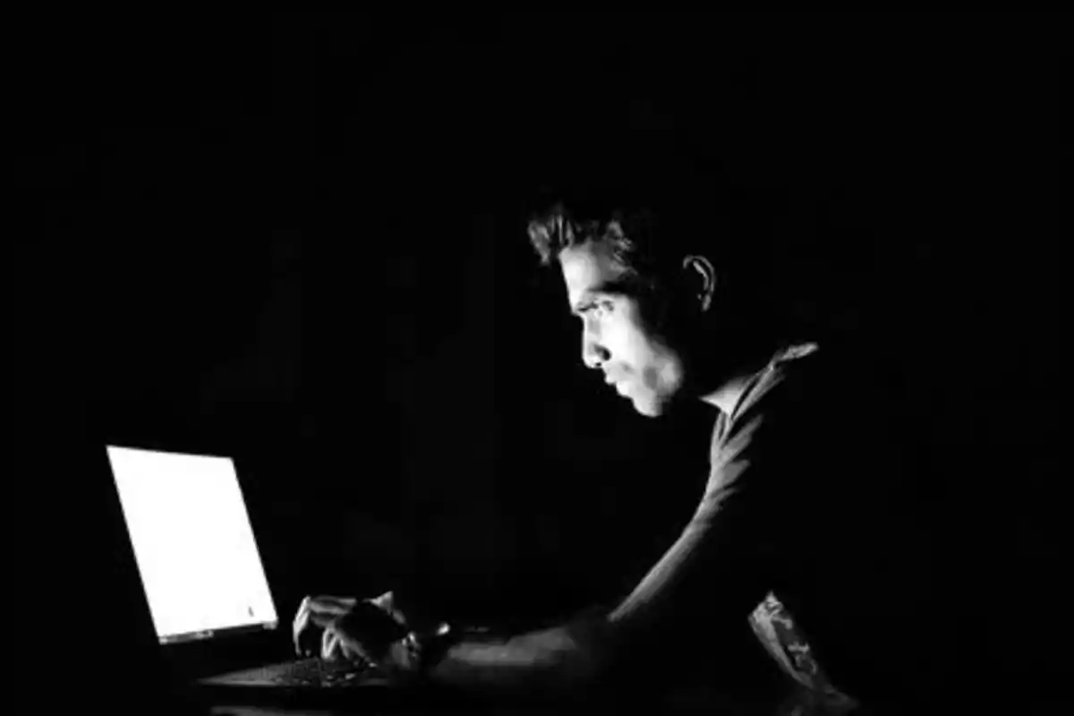 Persona usando una computadora portátil en la oscuridad.
