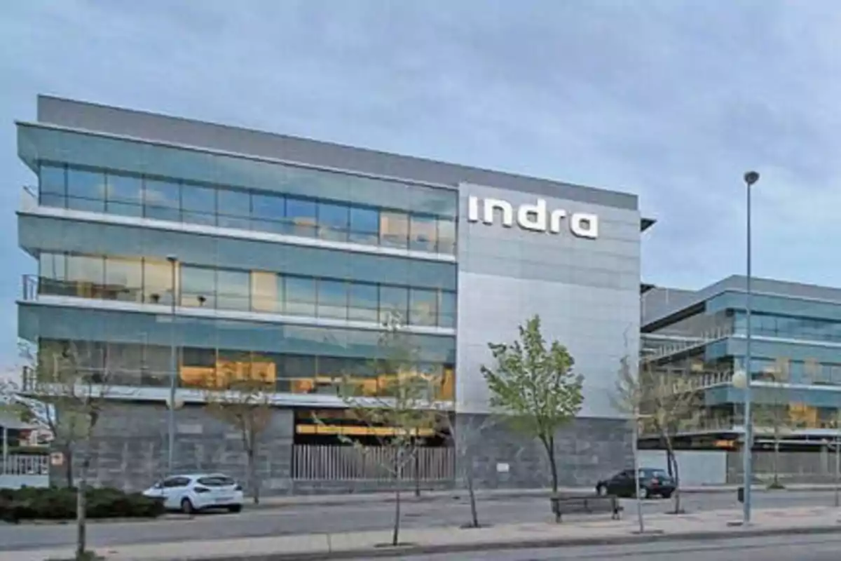 Edificio de oficinas de Indra con fachada de vidrio y metal en un entorno urbano.