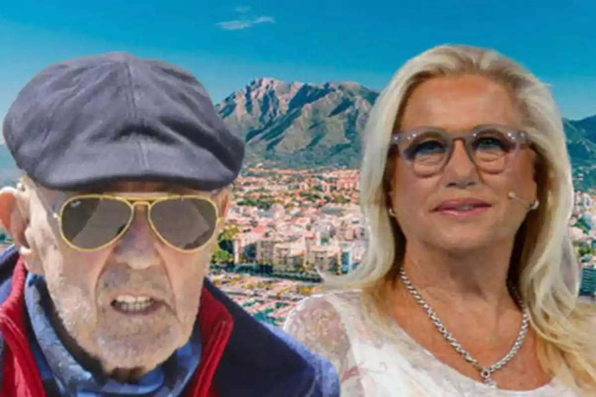 Dos personas mayores con gafas y sombreros posan frente a un paisaje montañoso y una ciudad.