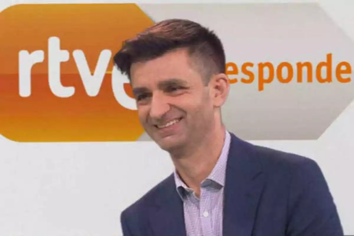 Hombre sonriendo frente a un cartel de RTVE responde.