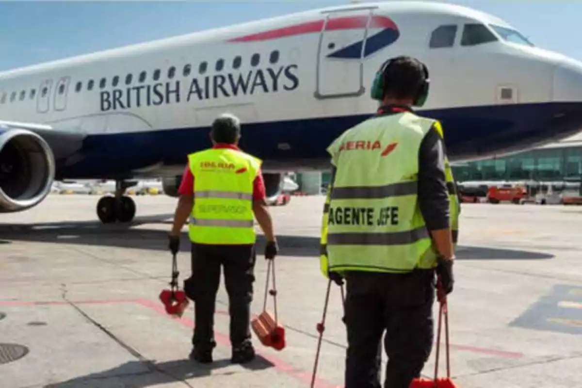Trabajadores de tierra de Iberia en el aeropuerto junto a un avión de British Airways.