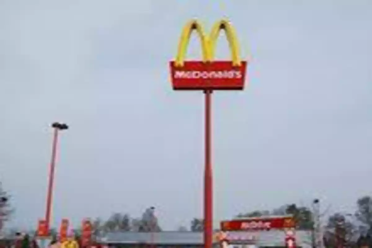 Letrero alto de McDonald's con el cielo nublado de fondo.