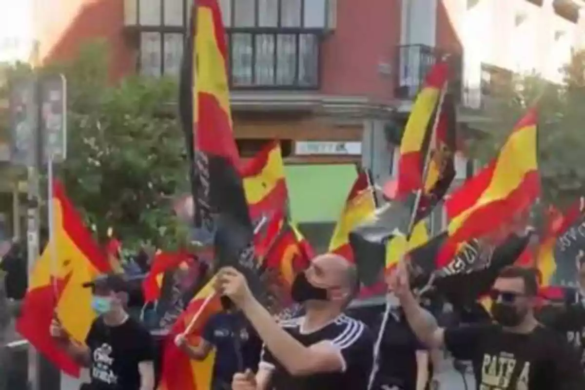 Personas con mascarillas sosteniendo banderas de España en una manifestación.