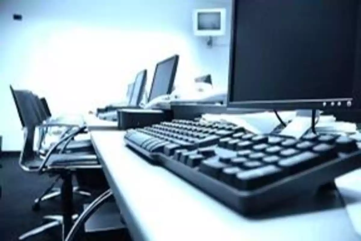 Oficina con varias estaciones de trabajo equipadas con computadoras y teclados.