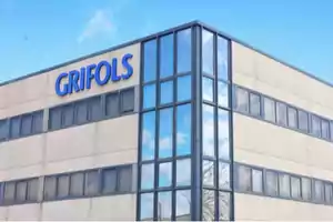 Edificio de oficinas de Grifols con fachada de vidrio y cielo despejado.