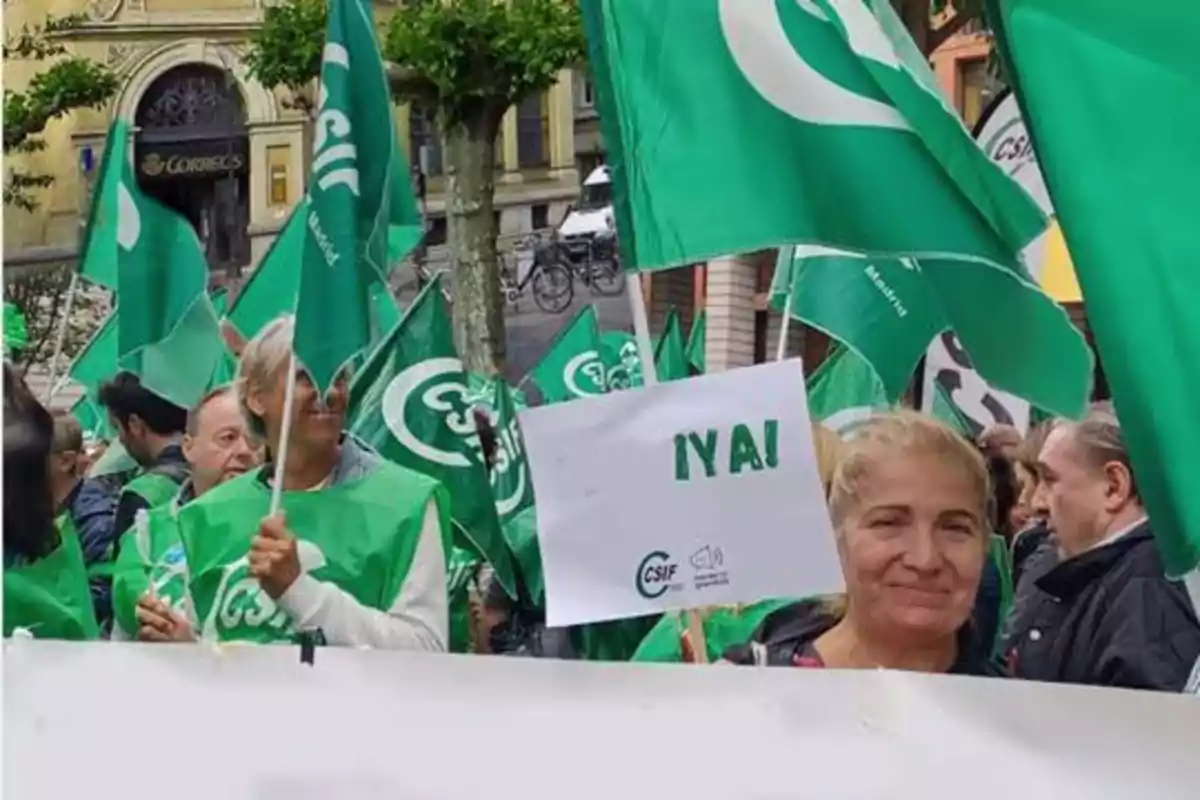 Un grupo de personas participa en una manifestación, llevando banderas verdes y chalecos con el logo de CSIF, mientras una mujer sostiene un cartel que dice "¡YA!".