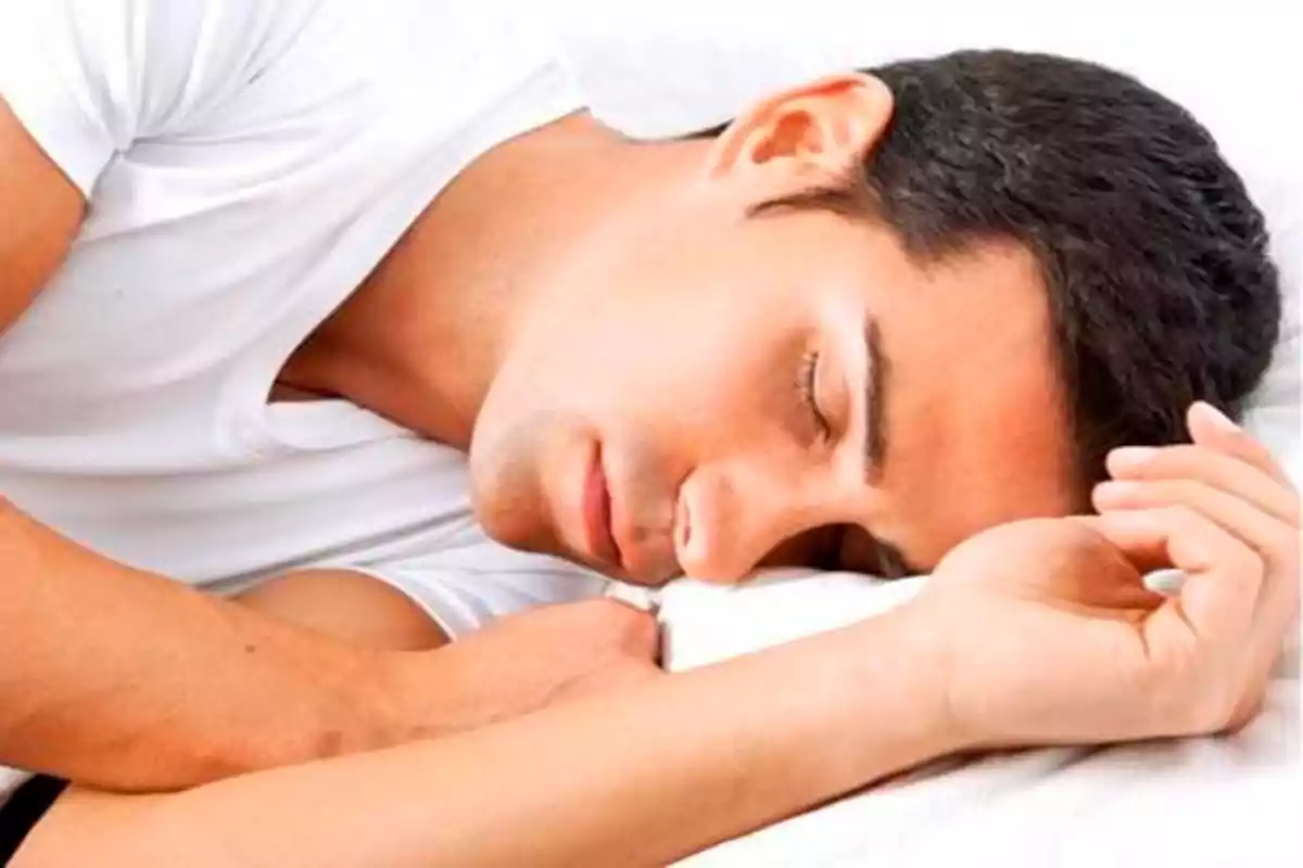 Hombre durmiendo sobre una almohada blanca.
