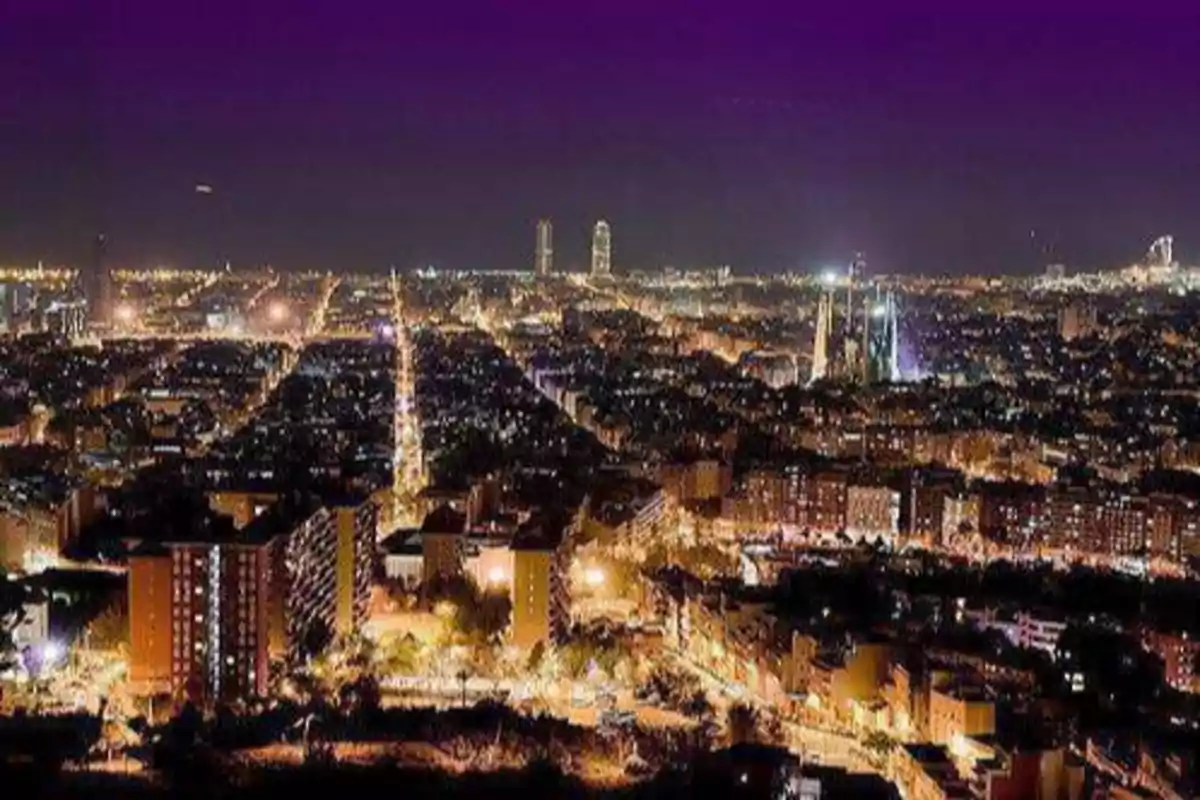 Vista nocturna de una ciudad iluminada con edificios y calles llenas de luces.
