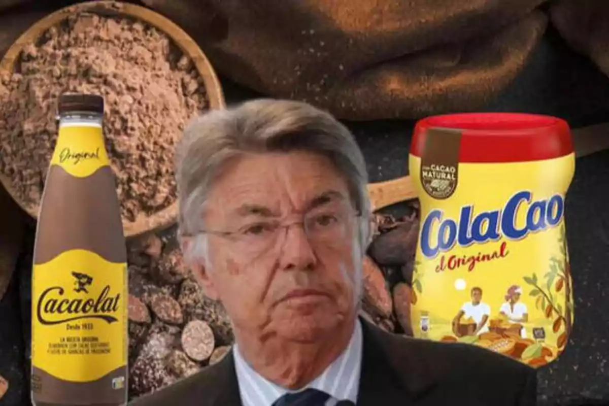 Un hombre mayor con gafas aparece en primer plano, mientras que en el fondo se ven productos de cacao, incluyendo una botella de Cacaolat y un bote de ColaCao.