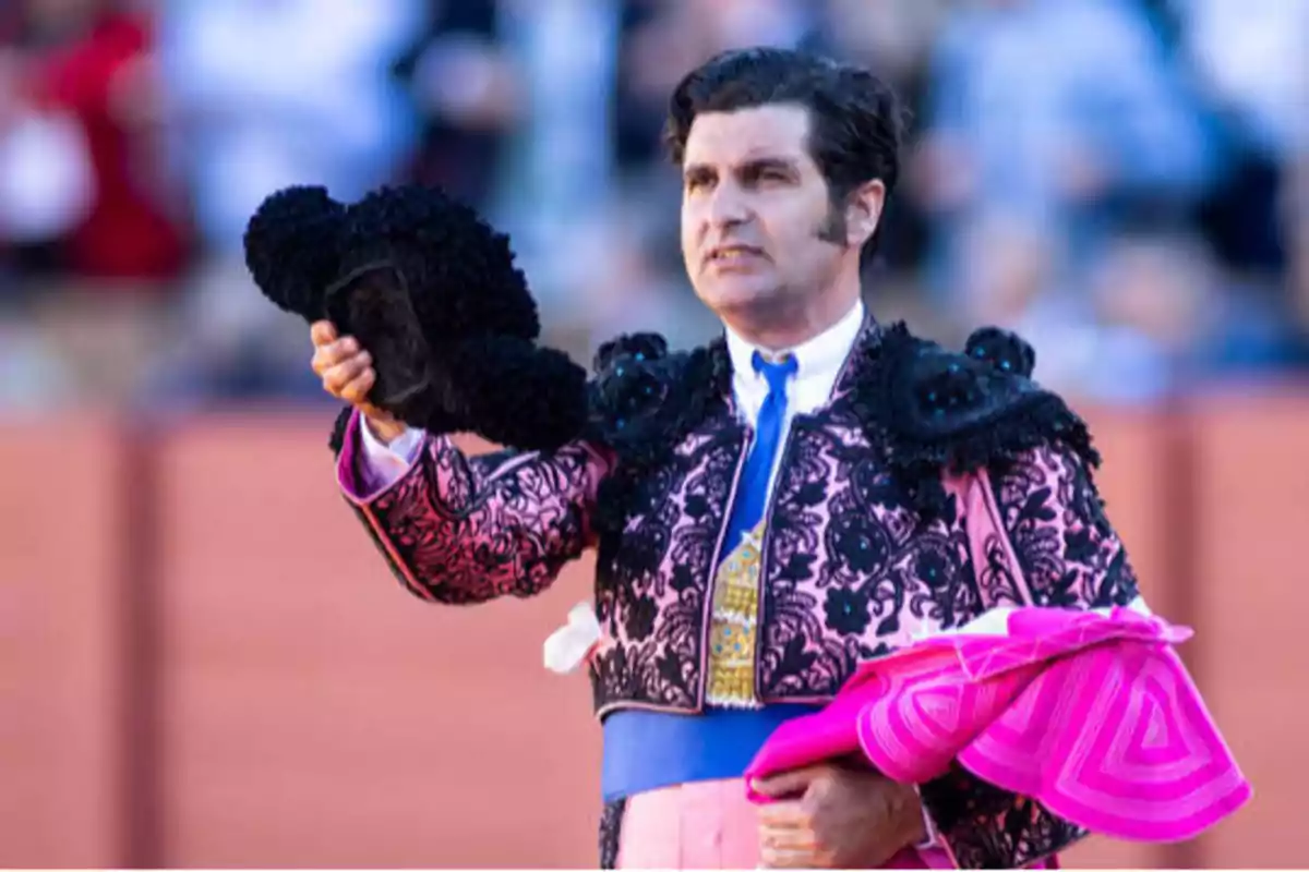 Un torero sosteniendo su montera y capote en una plaza de toros.