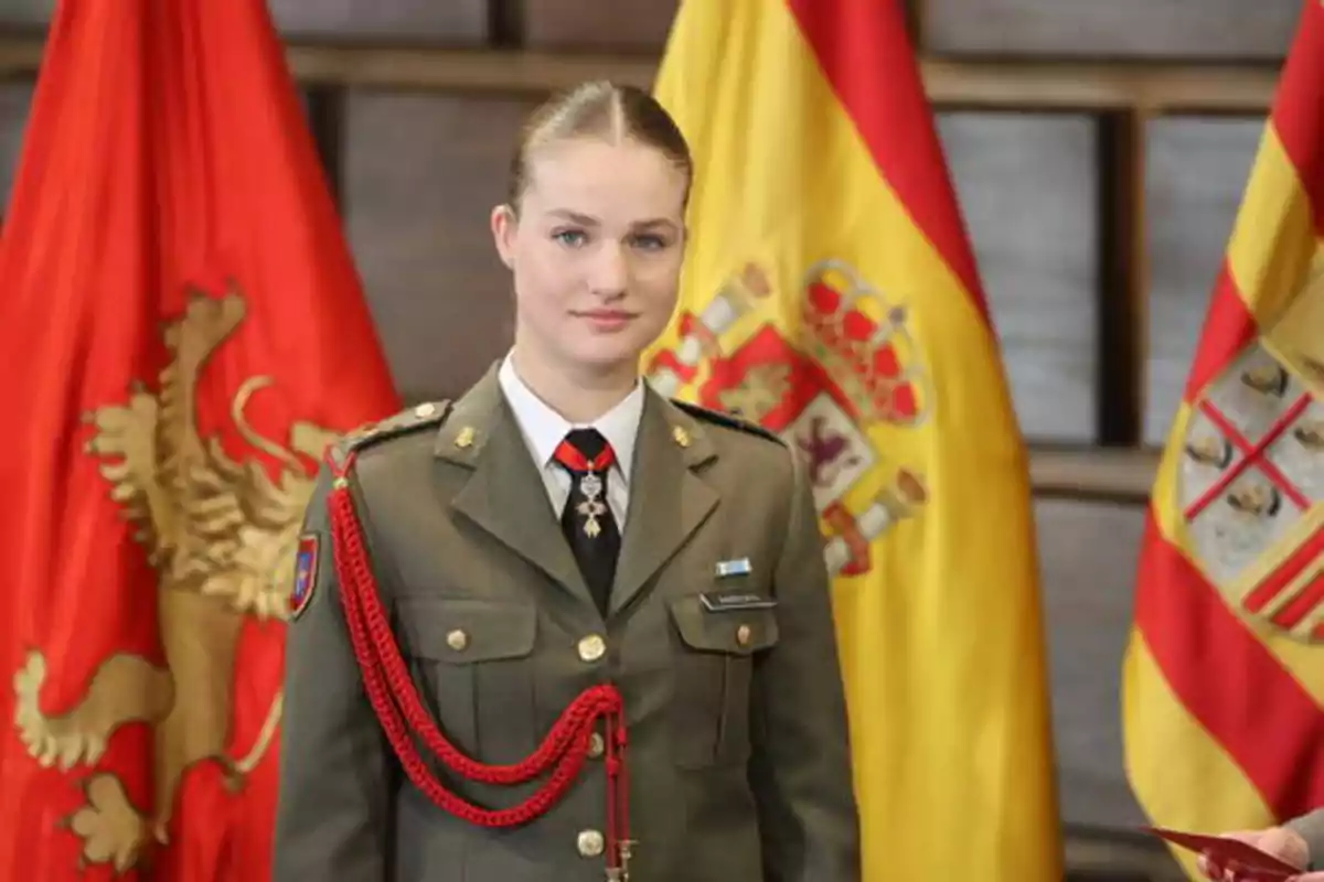Una mujer en uniforme militar posando frente a banderas oficiales.