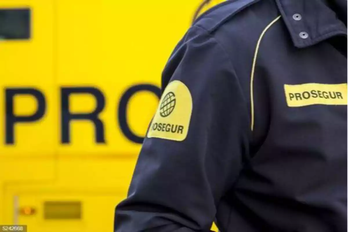 Uniforme de un guardia de seguridad de Prosegur frente a un vehículo amarillo de la misma empresa.