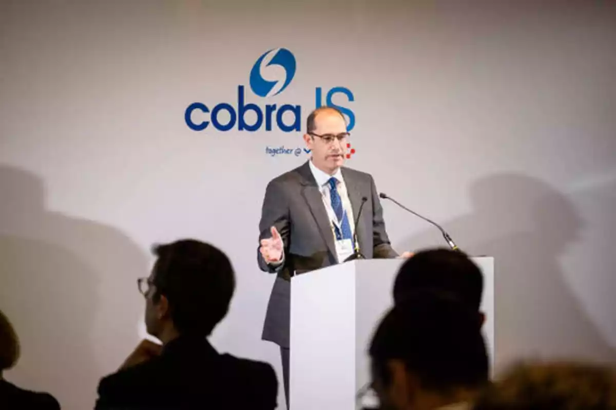 Un hombre de traje y corbata hablando en un podio durante una conferencia de la empresa Cobra IS.