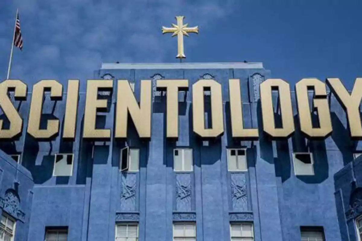 Edificio azul con la palabra "SCIENTOLOGY" en letras grandes y doradas, con una cruz dorada en la parte superior.