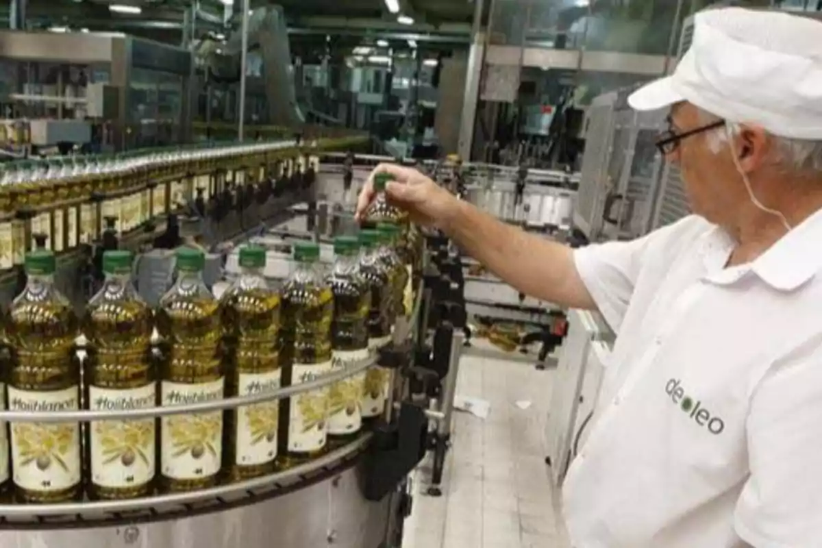 Trabajador inspeccionando botellas de aceite en una línea de producción de Deoleo.