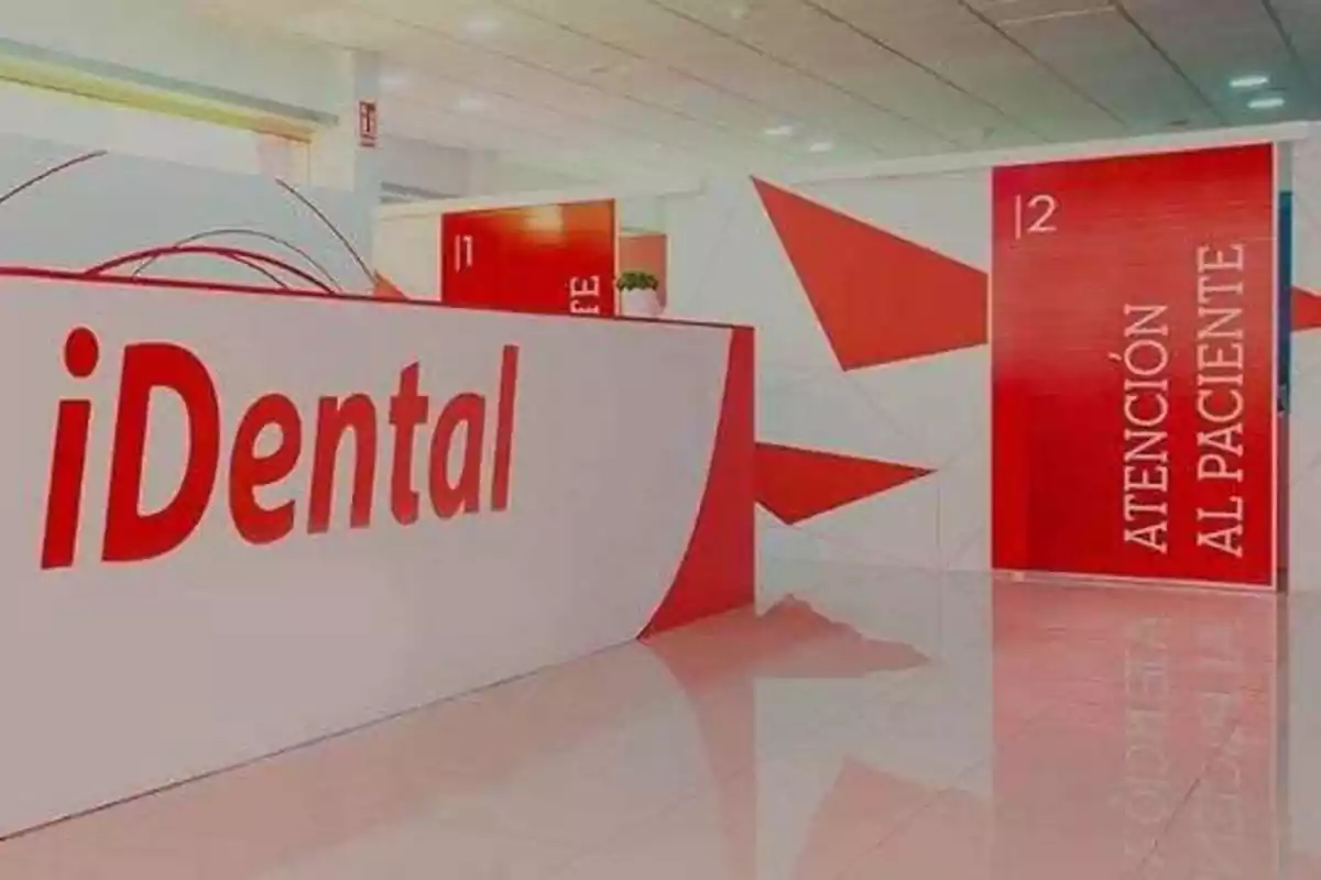 Recepción de una clínica dental con el nombre "iDental" en letras rojas y un letrero que dice "Atención al Paciente".