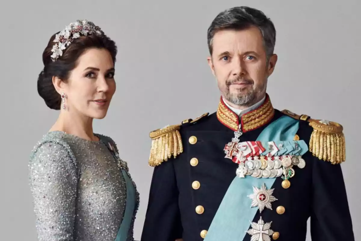 Una pareja vestida con trajes formales y condecoraciones, la mujer lleva un vestido brillante y una tiara, mientras que el hombre viste un uniforme militar con medallas.