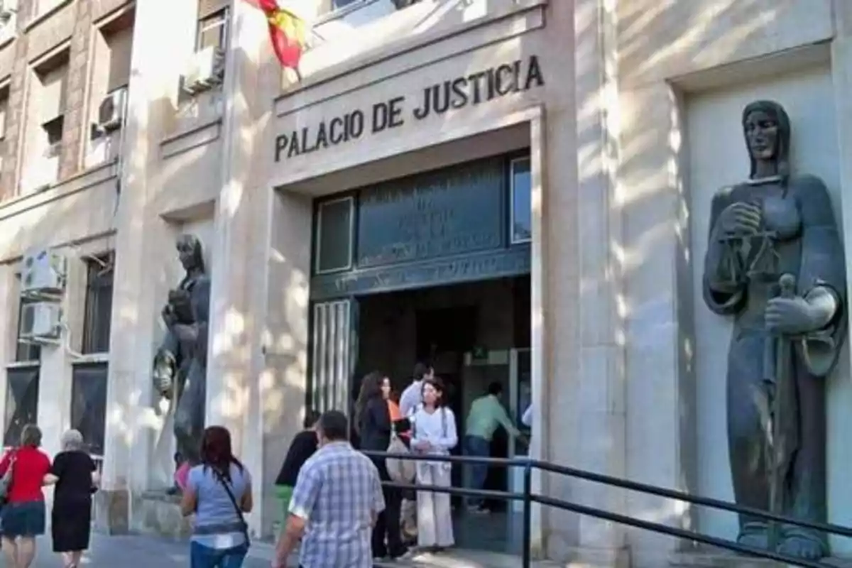 Entrada del Palacio de Justicia con varias personas entrando y saliendo del edificio.