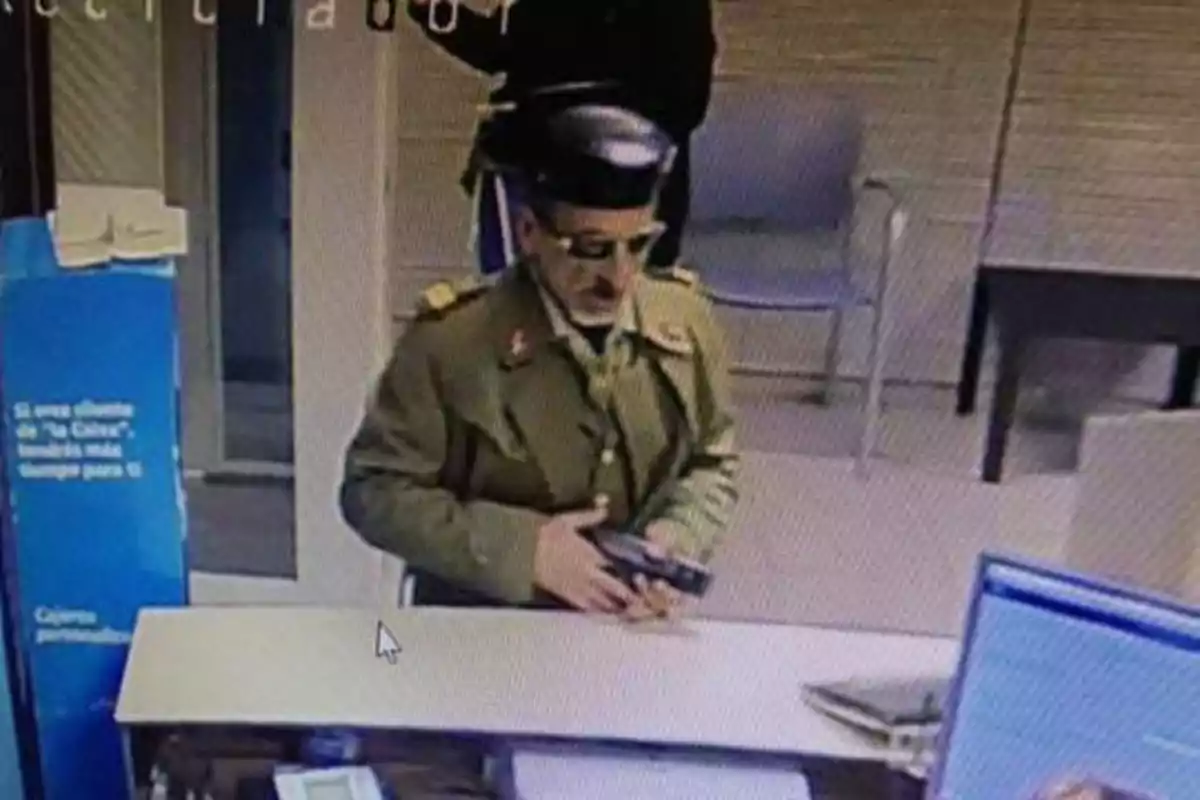 Un hombre vestido con uniforme militar y gafas de sol sostiene una pistola dentro de un edificio.