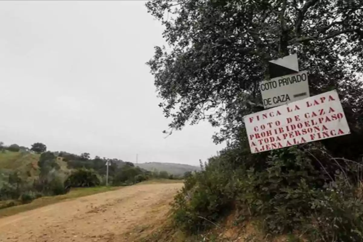 Un camino de tierra rodeado de vegetación con un cartel que indica "Coto Privado de Caza" y "Finca La Lapa, Coto de Caza, Prohibido el paso a toda persona ajena a la finca".