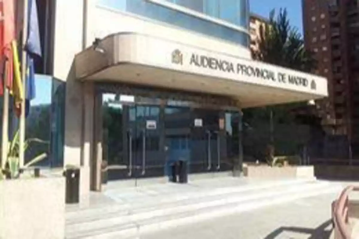 Fachada de la Audiencia Provincial de Madrid con banderas a la izquierda y edificios al fondo.