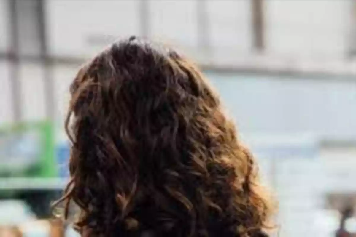 Persona de espaldas con cabello rizado en un entorno urbano.